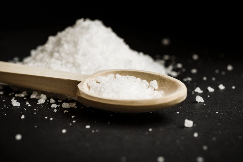 A close-up of coarse sea salt in a wooden spoon, highlighting sodium’s role in health and balance.